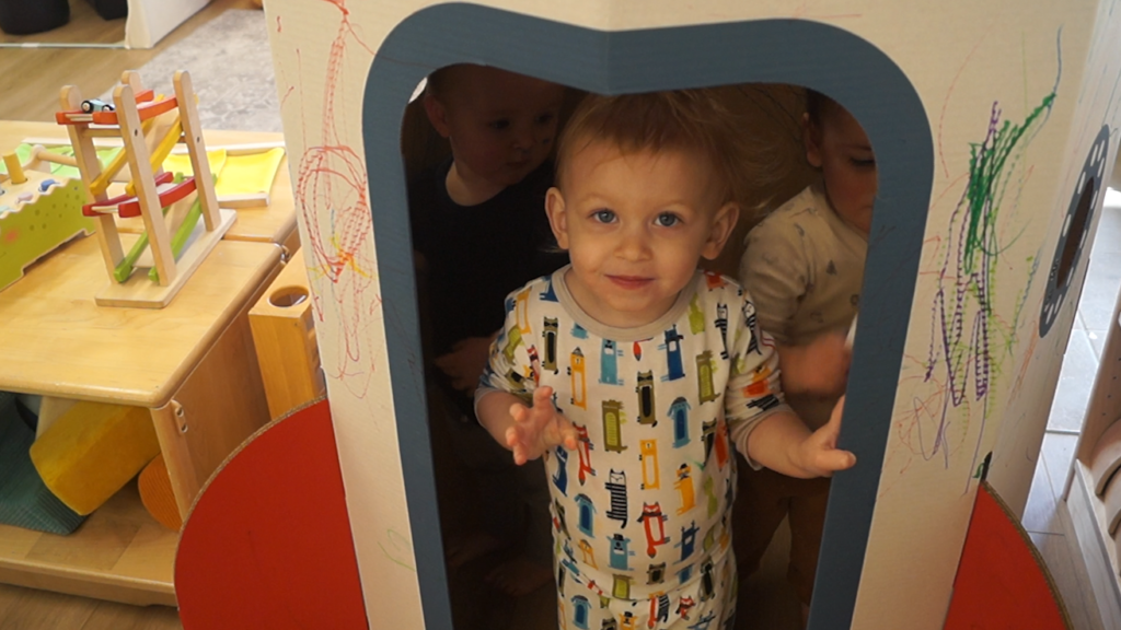 Toddlers play in carboard spaceship in a classroom at Inspired Play Learning Center.